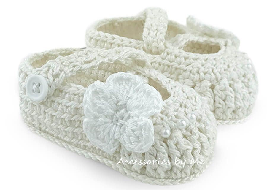 Ivory crochet baby shoes with a flower on a white background