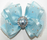 A light blue sheer ribbon hair bow with a central faux pearl and rhinestone, decorated with small silver rhinestones attached to a clip or headband.