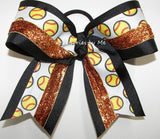 A cheer bow featuring a white grosgrain ribbon printed with yellow and red softball patterns, accented with black grosgrain ribbon and metallic orange copper glitter ribbon, tied into a large bow on a white background.